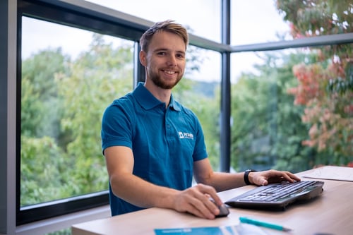 Ein freundlicher dualer Student im Bereich Wirtschaftsingenieurwesen an seinem Arbeitsplatz.