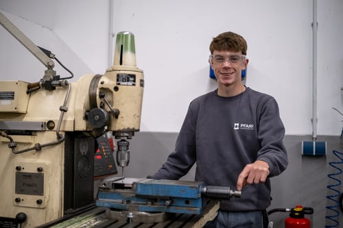 Freundlicher Mechatroniker (m/w/d) in Ausbildung an einer Maschine.